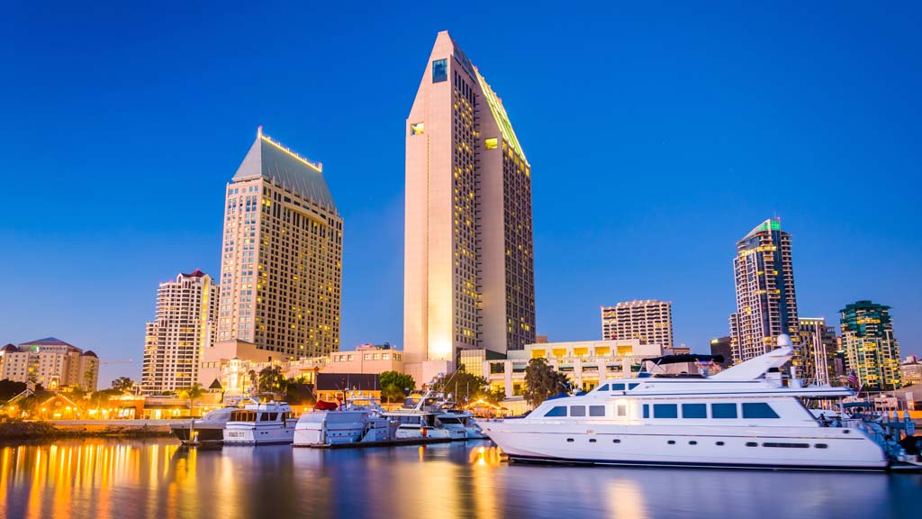 Vibrant cruise ship gliding across San Diego Harbor, with the city’s skyline